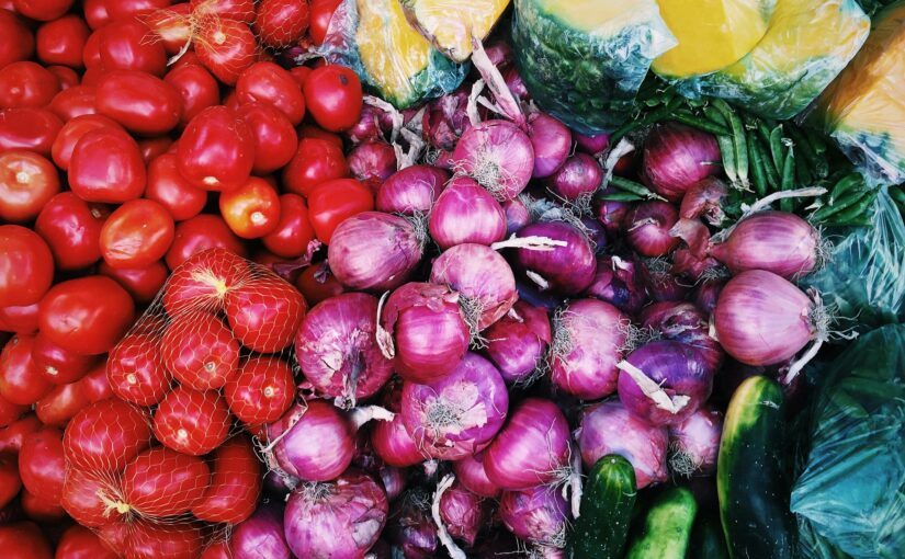 A group of brightly colored tomatoes, onions and cucumbers