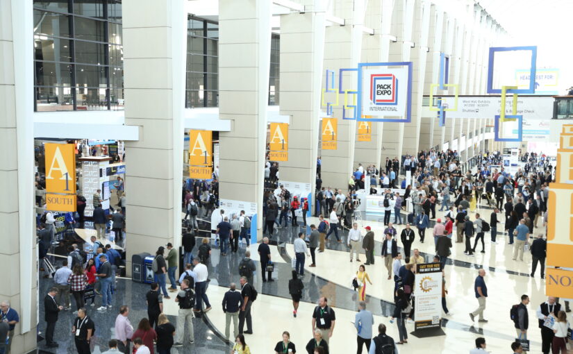 An overhead shot of people milling about an exhibition hall flooded with natural light