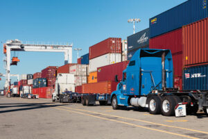 A tractor trailer sits behind a row of containers at the Port of Oakland