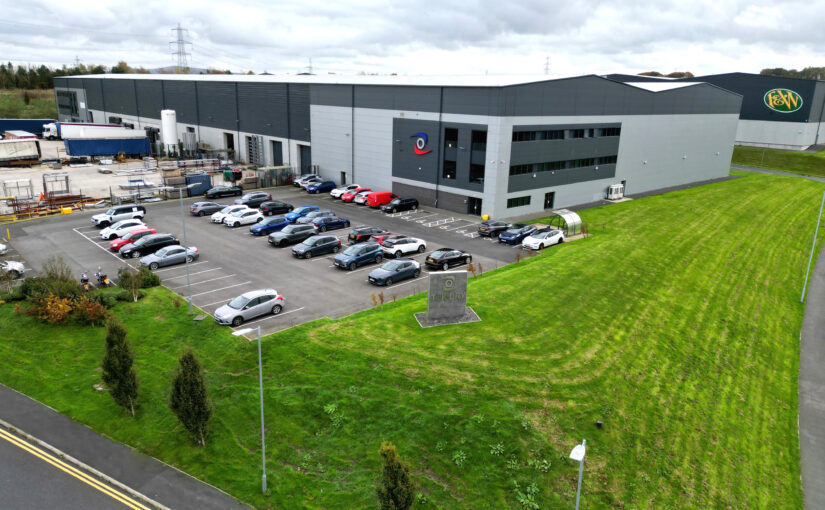A gray building with a dozen cars parked in front