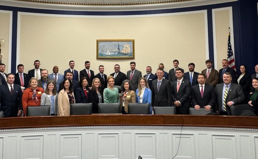 Dozens of men and women ring a dais