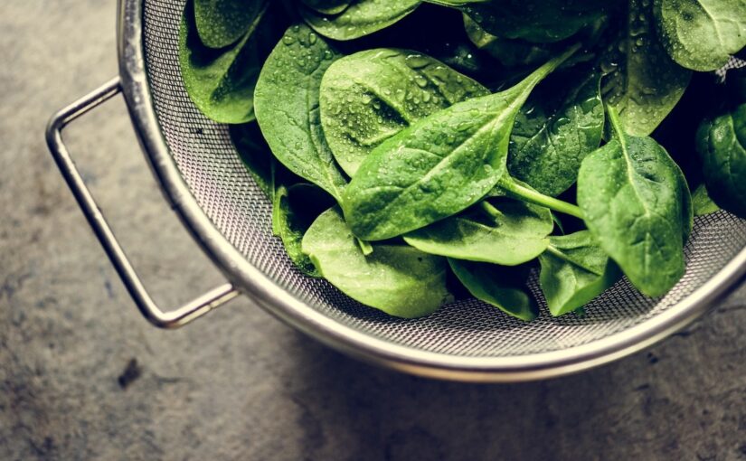 A closeup of freshly washed spinach leaves in a wire basket